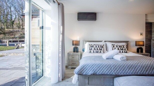 A bedroom with a large bed, a bedside table, a nightstand, a window, and a view of the outside. - Suite 10 - Sleeping Giant Hotel - Pen Y Cae Inn (Swansea Valley)