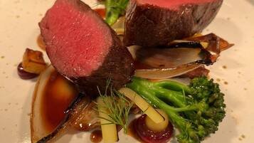 A plate of food with a slice of meat, vegetables, and sauce.