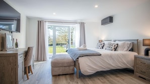 A modern bedroom with a large bed, a desk, a chair, and a television. - Suite 10 - Sleeping Giant Hotel - Pen Y Cae Inn (Swansea Valley)