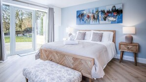Un dormitorio con una cama grande, un banco y un cuadro en la pared.