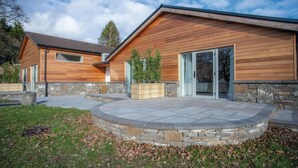 Una casa moderna con fachada de madera, base de piedra y un patio de piedra.