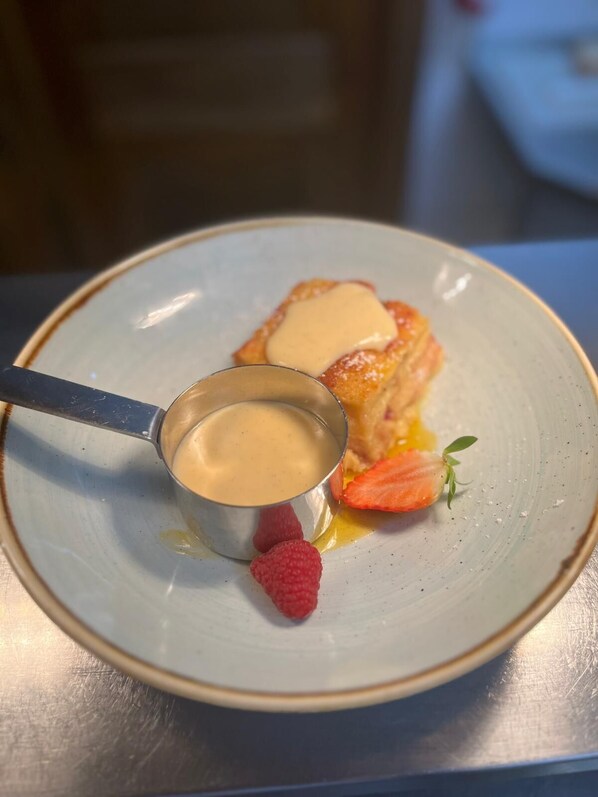 Un plato de postre con una bola de helado de vainilla y una fresa.