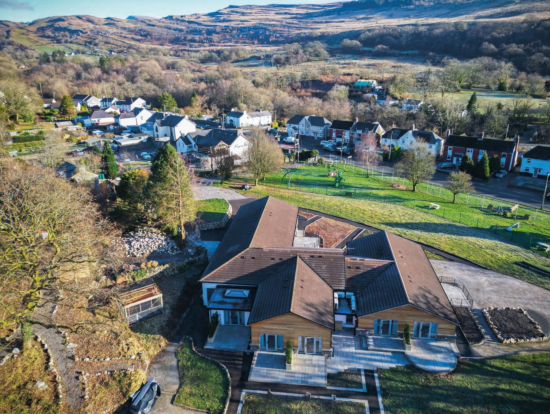 Un quartier résidentiel avec des maisons, une aire de jeux et un grand bâtiment doté d’un toit en pente.
