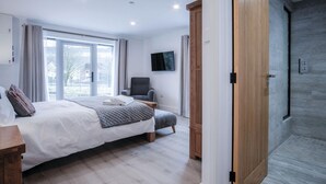 Une chambre moderne avec un grand lit, un bureau, une chaise et un téléviseur.
