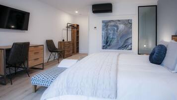 A modern bedroom with a large bed, a desk, a chair, and a wardrobe.