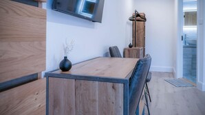 Una cocina moderna con una mesa de comedor de madera, un televisor de pantalla plana montado encima y un mueble de madera a la izquierda.