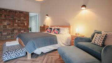 A modern bedroom with a large bed, a sofa, and a small table.