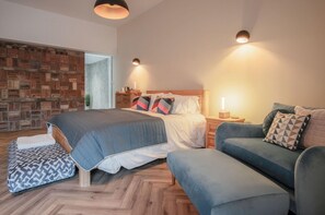 A modern bedroom with a large bed, a sofa, and a small table.