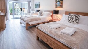 A hotel room with two beds, a wooden floor, and a view of the outdoors through a glass door. - Suite 3 - Sleeping Giant Hotel - Pen Y Cae Inn (Swansea Valley)