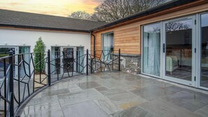 A modern house with a stone exterior, large glass sliding doors, and a paved patio area. - Suite 3 - Sleeping Giant Hotel - Pen Y Cae Inn (Swansea Valley)