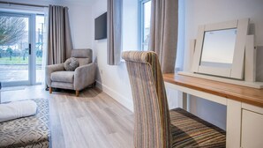 Ein modernes Wohnzimmer mit einer Couch, einem gestreiften Sessel, einem Holztisch und einem an der Wand montierten Fernseher.