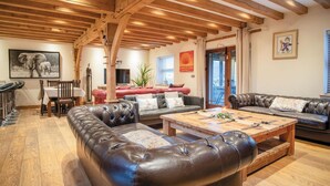 A spacious living area with leather sofas, a wooden coffee table, and exposed wooden beams on the ceiling. - Oak Lodge - Hot Tub - Pen Y Cae Inn (Swansea Valley)