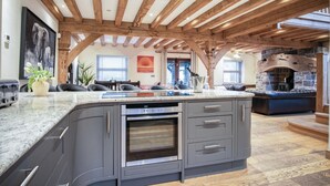 A kitchen with a central island, built-in oven, and grey cabinetry. - Oak Lodge - Hot Tub - Pen Y Cae Inn (Swansea Valley)