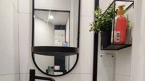 A bathroom with a white sink, black countertop, and a mirror above it.