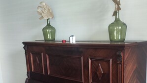 A dark wood bench with a white bench seat, positioned in front of a wooden cabinet with decorative carvings.