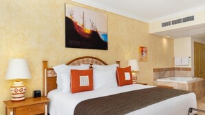 A hotel room with a bed, nightstands, a lamp, a painting, and a bathroom with a sink and mirror.