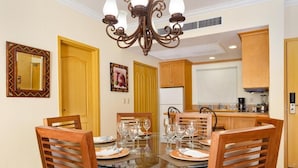 A dining area with a glass table, wooden chairs, and a chandelier.