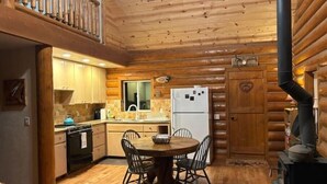 L’intérieur d’un chalet confortable, avec une salle à manger, une cuisine et une cheminée.