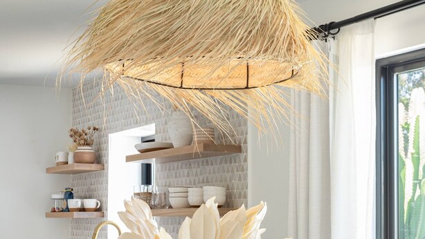 Una cocina moderna con una mesa de comedor de madera, sillas blancas y un jarrón decorativo.