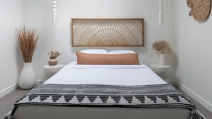 Un dormitorio moderno con una cama grande, cabecera de madera y una lámpara colgante.