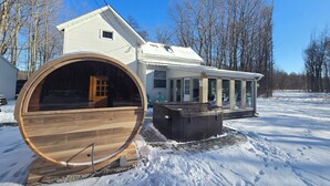 A house with a large wooden barrel, a hot tub, and a covered porch. - 14 Min to Lake Michigan: 3BR, 5 Beds, 30 Acres, Hot Tub, Sauna, Pets & Fire Pit (Covert)