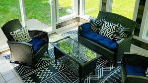 A sunlit patio with wicker furniture and patterned rugs, overlooking a green lawn. - 14 Min to Lake Michigan: 3BR, 5 Beds, 30 Acres, Hot Tub, Sauna, Pets & Fire Pit (Covert)