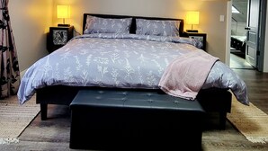 A bedroom with a bed, bedside lamps, a bench, and a ceiling light. - 14 Min to Lake Michigan: 3BR, 5 Beds, 30 Acres, Hot Tub, Sauna, Pets & Fire Pit (Covert)