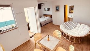 A compact hotel room with a bed, a small table with chairs, a window, and a bathroom visible in the background. - Holiday bungalow for two, Sainte Anne beach (Sainte-Anne)