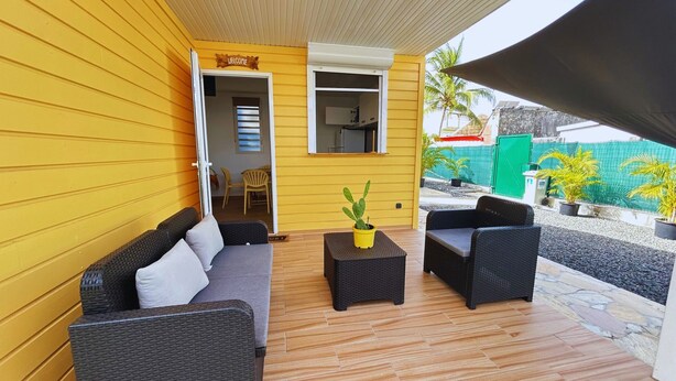 A covered outdoor seating area with wicker furniture and a potted plant. - Holiday bungalow for two, Sainte Anne beach (Sainte-Anne)
