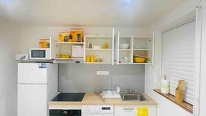 A compact kitchen with a microwave, oven, dishwasher, and a sink. - Holiday bungalow for two, Sainte Anne beach (Sainte-Anne)