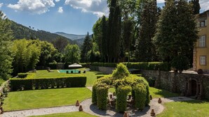Ein gepflegter Garten mit Schwimmbad, ordentlich geschnittenen Hecken und einer Steinmauer.