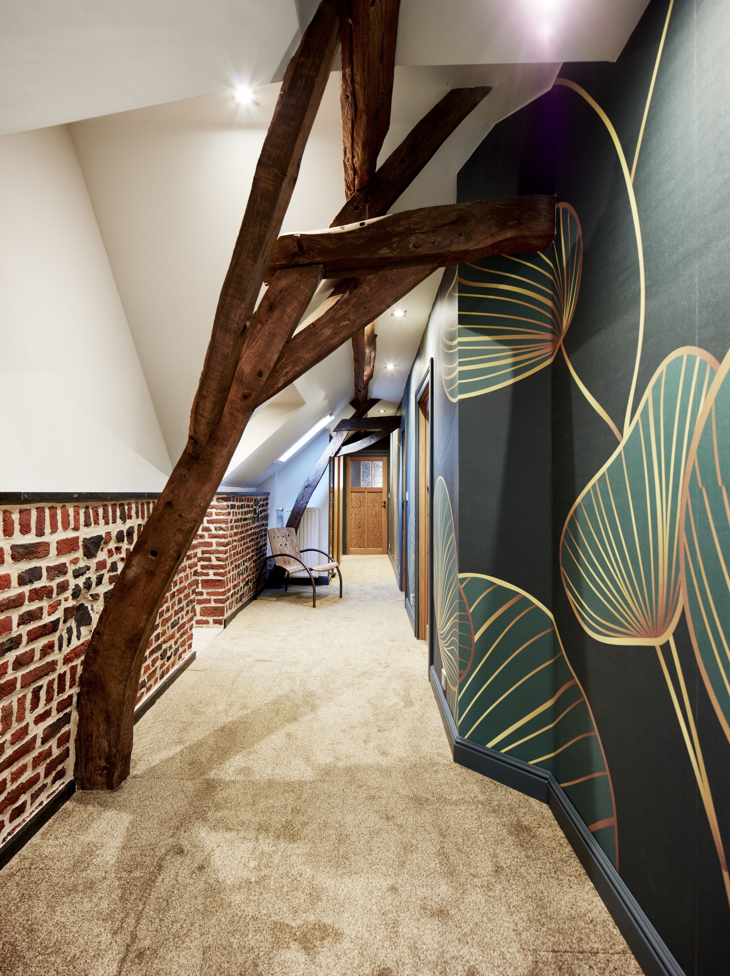 A hallway with exposed wooden beams, brick walls, and a carpeted floor.