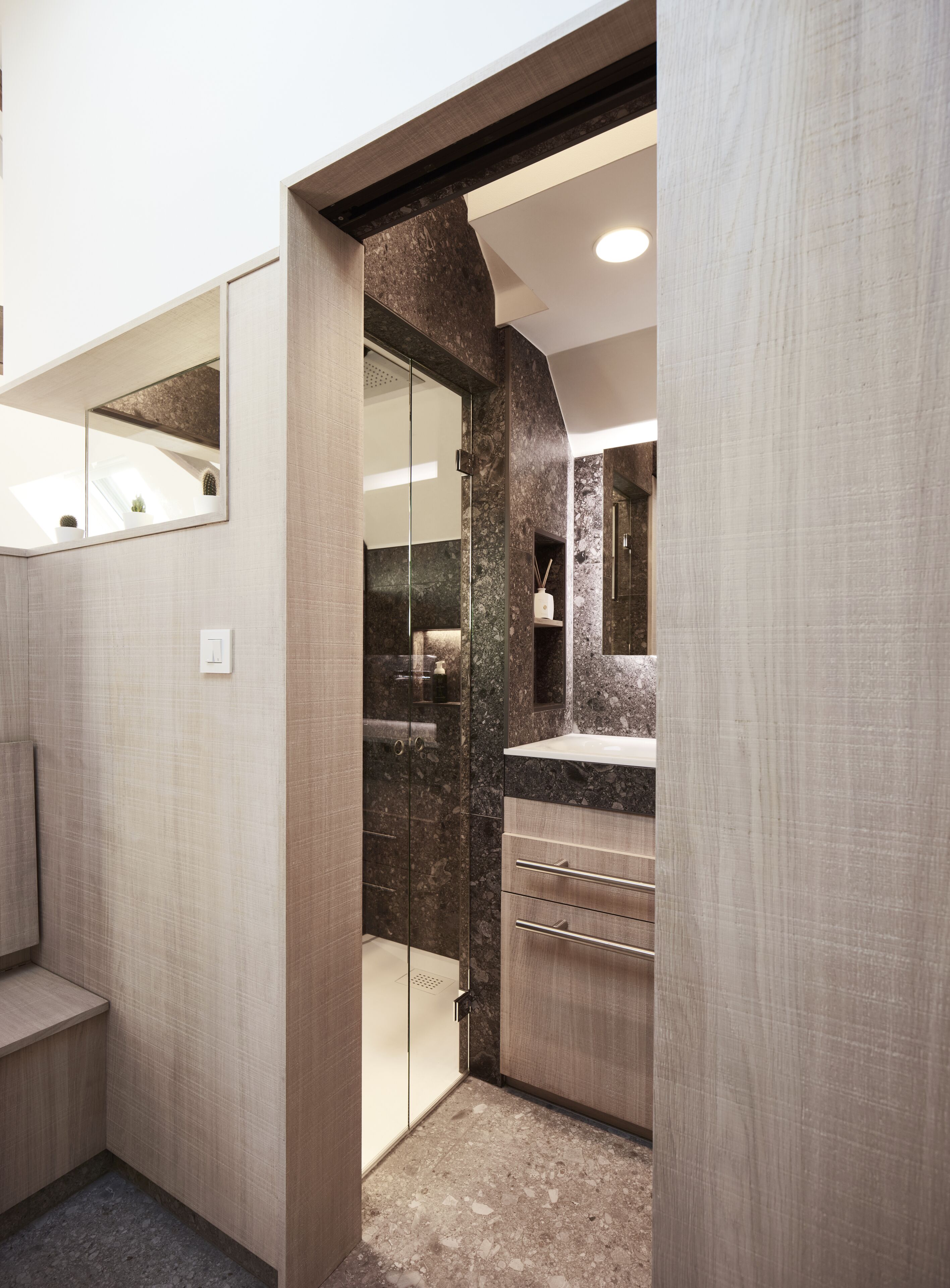 A modern bathroom with a glass shower enclosure, a marble countertop, and a built-in sink.