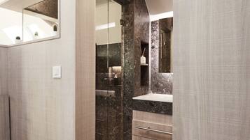 A modern bathroom with a glass shower enclosure, a marble countertop, and a built-in sink.