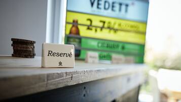 Uma pequena placa com a palavra 'Reserved' numa superfície de madeira, com um fundo desfocado mostrando uma placa com a palavra 'VEDETT' e algum texto.