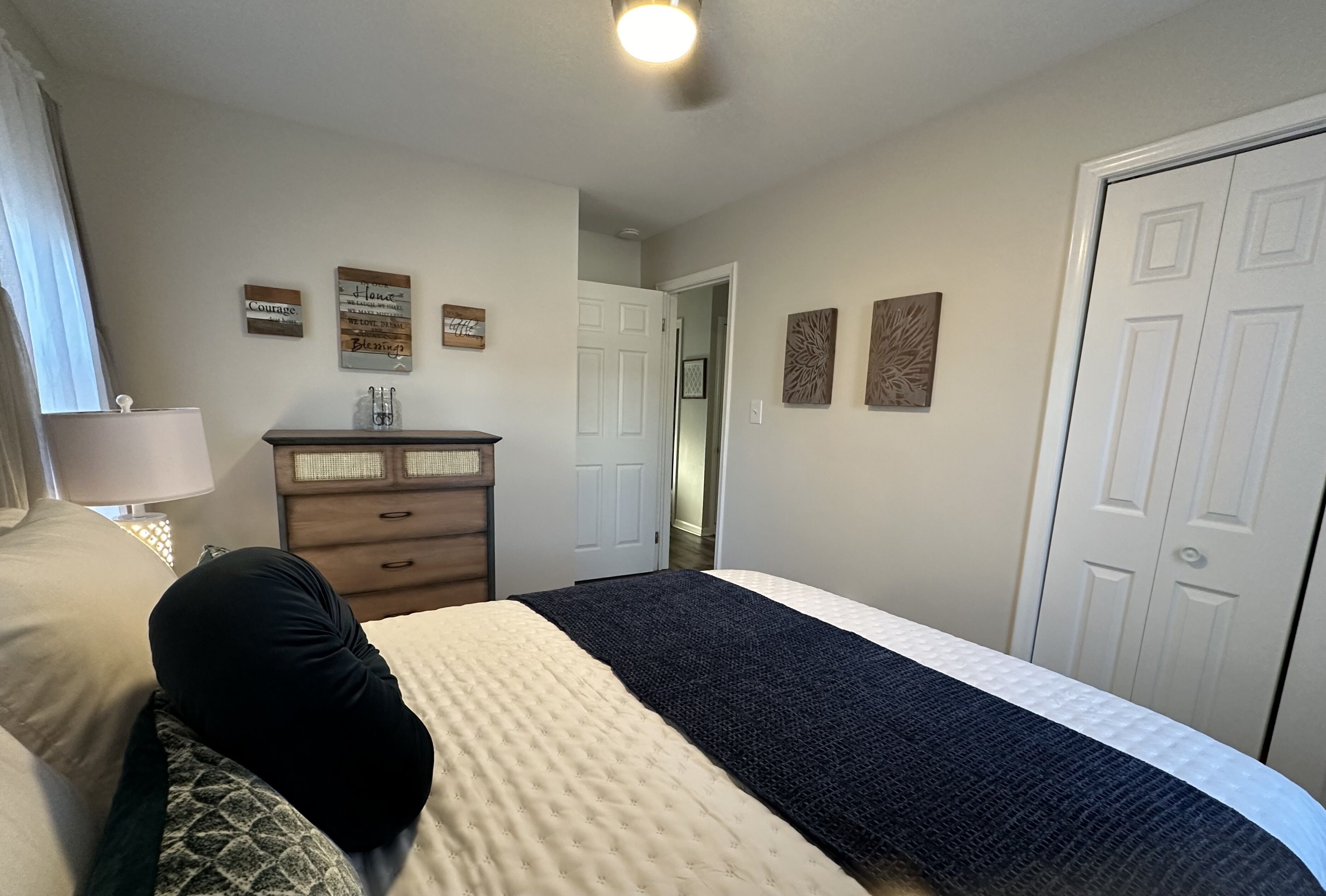 A bedroom with a bed, dresser, and wall decorations.