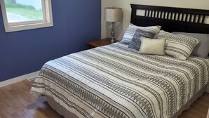 Une chambre à coucher avec un lit, une table de chevet, une lampe et une fenêtre.