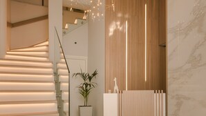 Et moderne interiør med trappe, en træreception, en potteplante og en læderstol.
