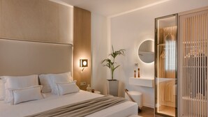 Et moderne hotelværelse med en stor seng, et natbord, en potteplante, et rundt spejl og en skydelåge garderobe.