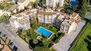 Eine Vogelperspektive eines Wohnkomplexes mit mehreren Mehrfamilienhäusern, einem zentral gelegenen Schwimmbecken und einer gepflegten Grünanlage.