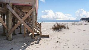 Una estructura de madera en la playa con una escalera que lleva a una plataforma.