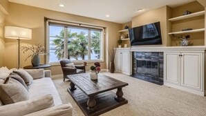A living room with a sofa, coffee table, and a fireplace. - Stunning Luxury Waterfront Home (Sammamish)