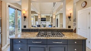 A kitchen with a granite countertop, dark cabinetry, and a gas stove. - Stunning Luxury Waterfront Home (Sammamish)