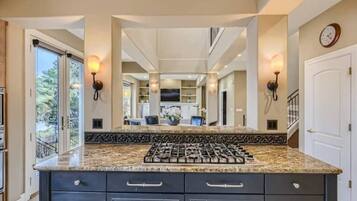 A kitchen with a granite countertop, dark cabinetry, and a gas stove.