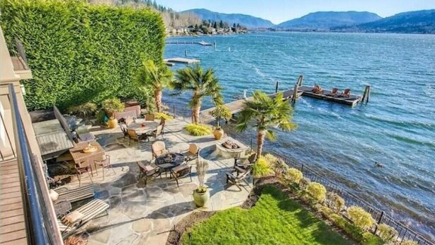 A patio area with stone flooring, outdoor furniture, and a view of a lake with boats. - Stunning Luxury Waterfront Home (Sammamish)