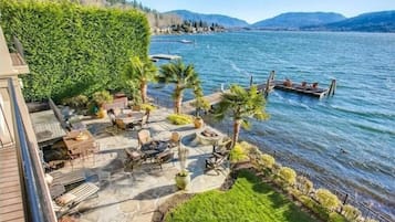A patio area with stone flooring, outdoor furniture, and a view of a lake with boats.