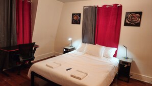 A neatly made bed with white linens, a desk with a chair, two bedside tables with lamps, and two framed pictures on the wall. - SPACIOUS AND QUIET (Meriden)