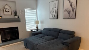 Ein modernes Wohnzimmer mit einer Eckcouch, einem Kamin und Wandbildern.
