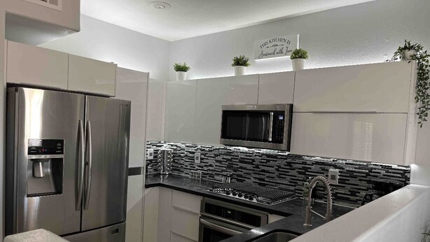 Eine moderne Küche mit Edelstahlgeräten, einer schwarzen Spritzschutzwand und einem Schild an der Wand.
