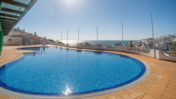 A rooftop swimming pool with a clear view of the sea and a cityscape in the background. - Colibri Apartment by HelloVacations (Albufeira)